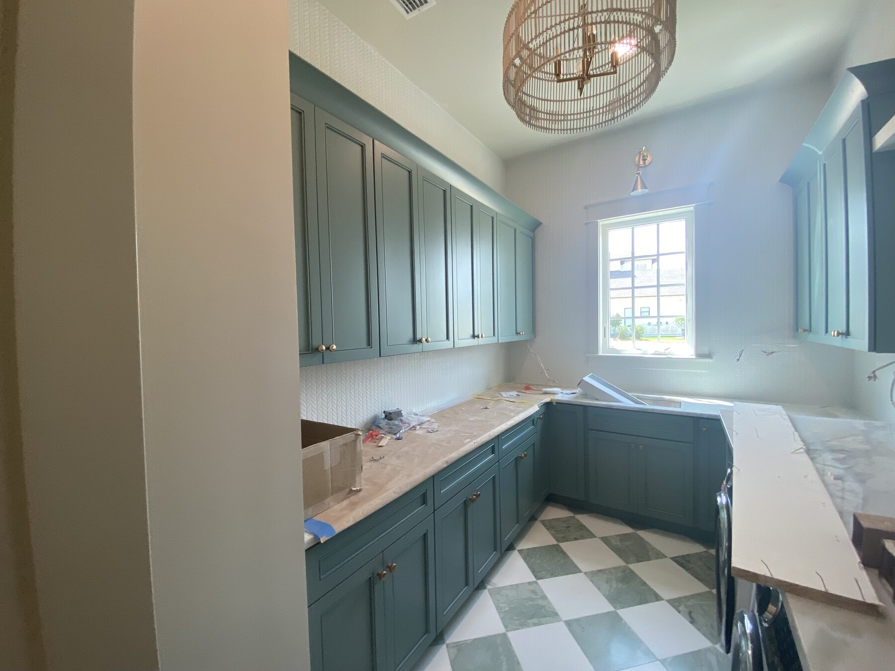 Laundry room with blue-green painted cabinetry, marble counters and a green and white checkerboard tile floor